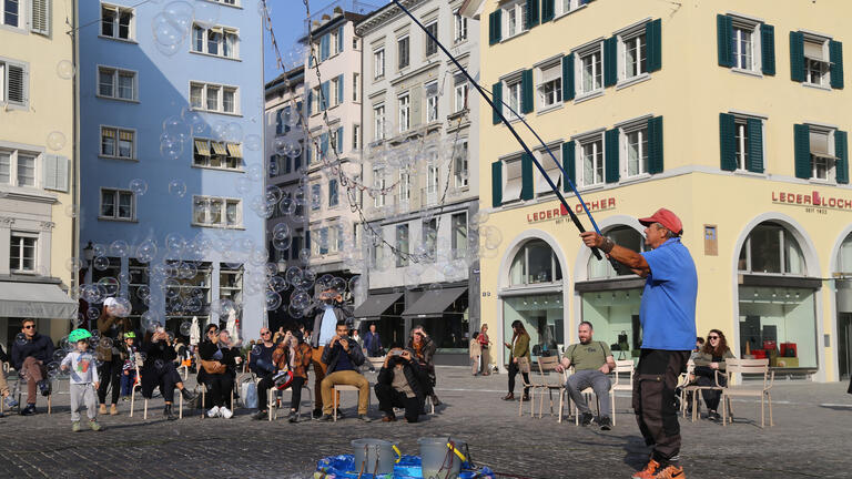 a man makes bubbles in a public plaza