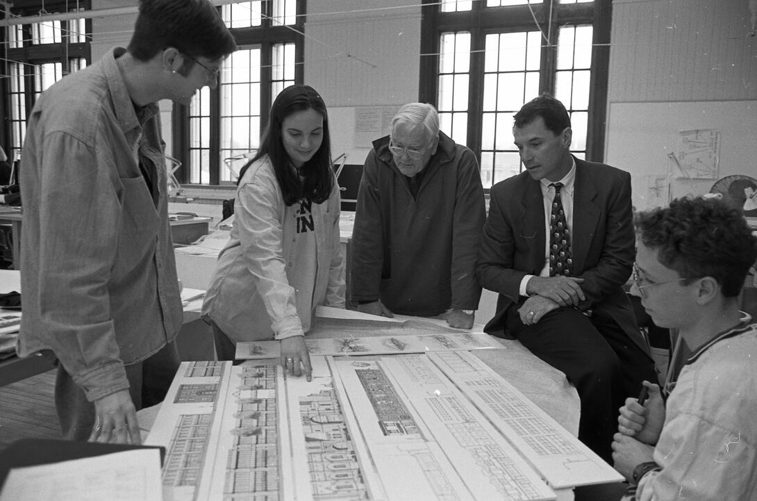 faculty and students look at an architectural drawing